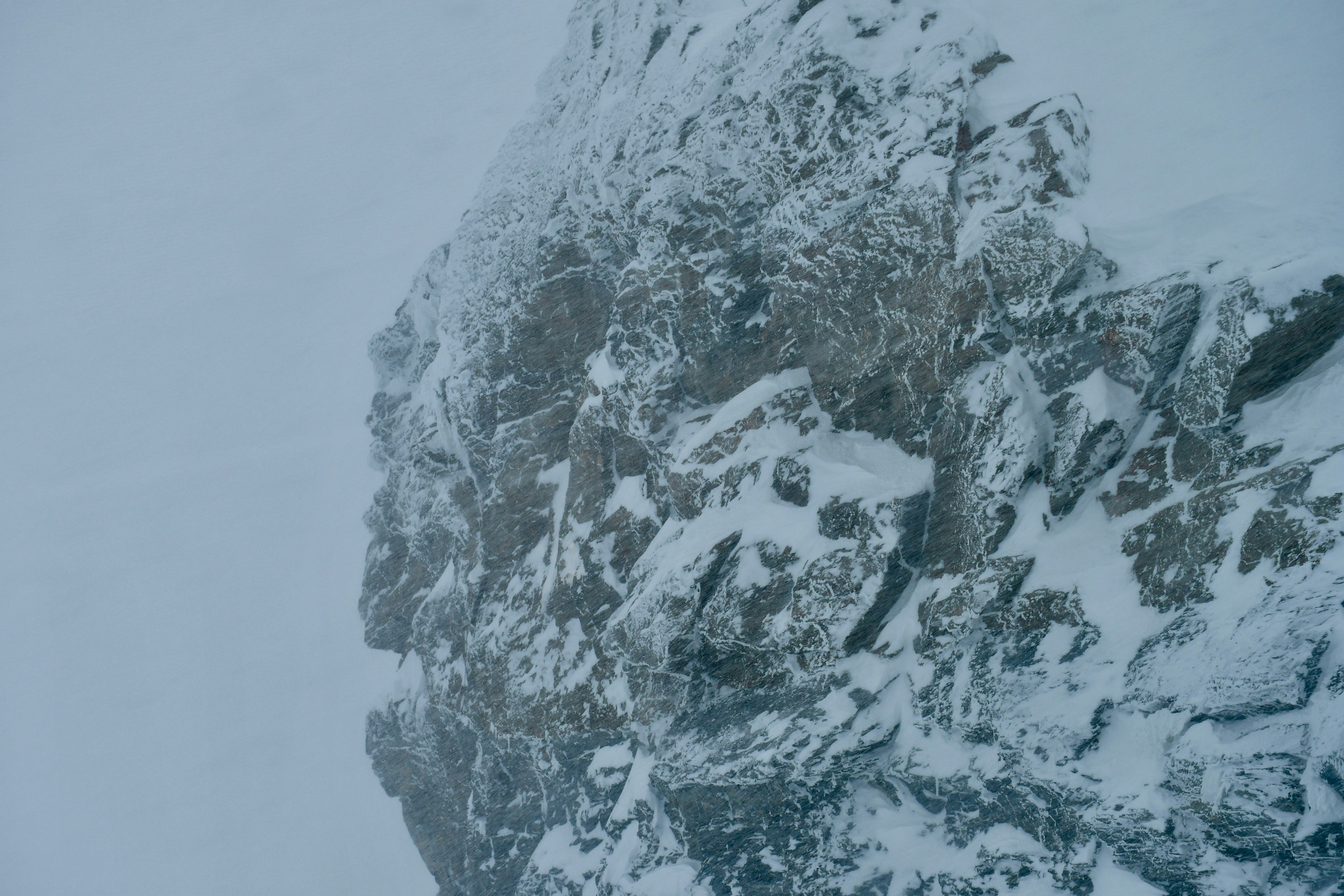 snow capped hill under storm